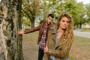 woman and man wearing brown jackets standing near tree
