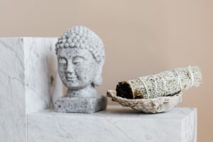 bust of buddha and dry sage bundle on marble surface