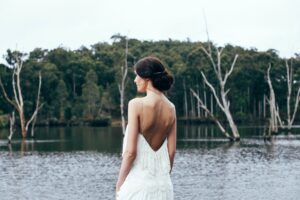 anonymous elegant bride standing near lake