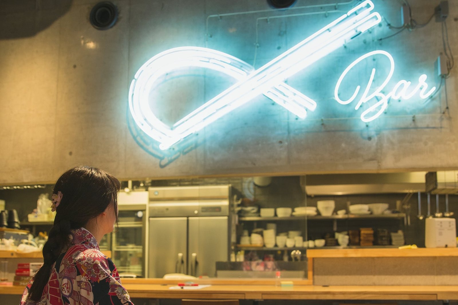 stylish woman looking on glowing signage in bar