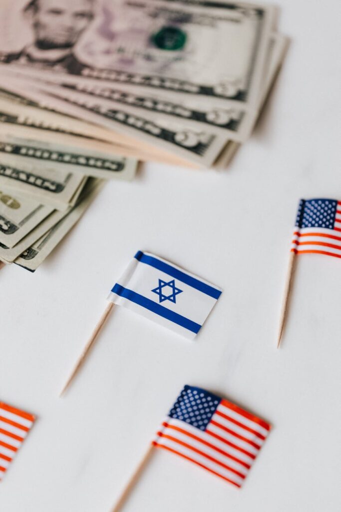 usa and israel mini flags on table with dollars